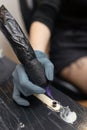 tattoo artist preparing a tattoo machine, dipping the needle into black ink Royalty Free Stock Photo
