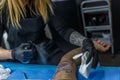 A tattoo artist woman with a spray on the arm of a client