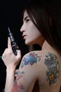 Tattoo asian woman artist holding tattoo machine on dark background