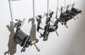 Tattoo coil ink machines hanging from hooks on white wall