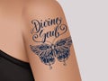 Tattoo on female shoulder. Mystic butterfly tattoo with lettering Divine Soul.