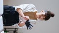 Tattoo girl wear rubber gloves at workplace vertical. Tattooist receiving client