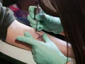 Tattoo master makes a tattoo. close-up of hands and typewriter. green gloves. close up