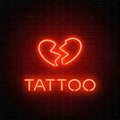 Tattoo parlor glowing neon signboard with emblem. Broken heart glowing logo on a brick wall background.
