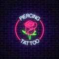 Tattoo and piercing parlor glowing neon signboard with rose emblem. Flower symbol in circle frame with text. Royalty Free Stock Photo