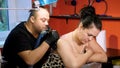 In a tattoo salon , a specialist is doing a tattoo on woman`s back, a floral ornament. a man works in special gloves, on