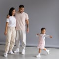 Tattooed asian man hugging wife near toddler daughter dancing on grey background Royalty Free Stock Photo