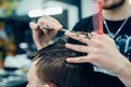 Tattooed Barber cuts the hair of the client with scissors. Close up. Attractive male is getting a modern haircut in Royalty Free Stock Photo