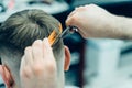 Tattooed Barber cuts the hair of the client with scissors. Close up. Attractive male is getting a modern haircut in Royalty Free Stock Photo