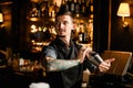 Tattooed bartender holding in hands a steel shaker with a deliciouds cocktail Royalty Free Stock Photo