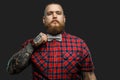 Tattooed bearded unformal male in red shirt and grey bow tie.