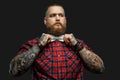 Tattooed bearded unformal male in red shirt and grey bow tie. Royalty Free Stock Photo