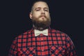 Tattooed bearded unformal male in red shirt and grey bow tie.