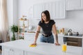 Tattooed brunette woman cleaning worktop with Royalty Free Stock Photo
