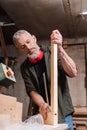 tattooed carpenter checking wooden plank in