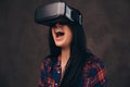 Tattooed girl wearing a red unbuttoned checked shirt wearing a VR headset.