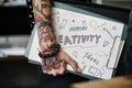 Tattooed hand holding a creativity clipboard