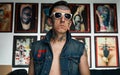 Tattooed man in denim vest and sunglasses in studio