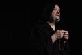 tattooed monk in hooded cassock praying