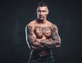 A muscular tattooed man over dark background.