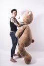 Tattooed natual looking woman playing with giant teddy bear