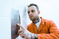 tattooed prisoner in orange uniform pressing button Royalty Free Stock Photo