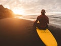 Tattooed senior surfer holding surf board on the beach at sunset - Happy old guy having fun doing extreme sport - Joyful elderly