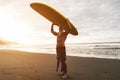 Tattooed senior surfer holding surf board on the beach at sunset - Happy old guy having fun doing extreme sport - Joyful elderly