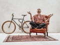 Tattooed stylish gangster sits on a armchair in a lotus pose, looks very expressive and freakly