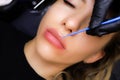 tattooist applies anesthesia to the contour of the model`s lips with a small brush