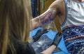 A tattooist girl is covering carefully a tattoo on the arm of a boy