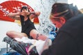 tattooist girl making a new tattoo on a customer& x27;s leg sitting on the table, full shot