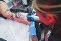 tattooist girl making a tattoo on a leg, tattoo studio concept