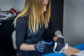 A tattooist girl shaves a part of an arm of her client