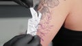 The tattooist glues a tattoo stencil to a girl`s arm.