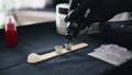 Tattooist hand dropping ink at workplace closeup. Master pouring black colour