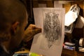 Tattooist looking at a drawing designed on a sheet of paper in a tattoo studio