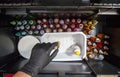 Tattooist selects a color from a box full of tattoo ink bottles
