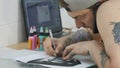 Tattooist talks on the phone and redrawing the sketch with carbon paper