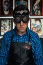 Tattooist in welder glasses and leather apron