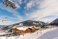 Blue sky and liftchait over mountain restaurant and snow-covered roof and mountains at tjhe background.