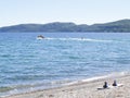 Ski wake-board on beach with towboat and skier in distance in bay on lake