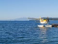 Tourist float plane at pier refueling on on popular traveler attraction with mountains in distance across lake