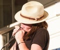 Musician closeup playing harmonica and wearing hat