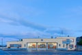 Deco style fire station at twilight with interior illuminated through doors