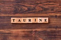 Taurine word lettering made of wooden cubes on dark rustic wooden background. Taurine helps to improve energy metabolism in the