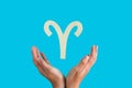 Astrological sign hanging over female hands on blue background