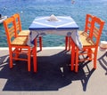 Tavern with orange wooden chairs by the sea coast, Santorini Royalty Free Stock Photo