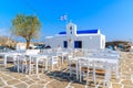Tavern tables on square with typical white Greek church in Naoussa fishing port, Paros island, Greece Royalty Free Stock Photo