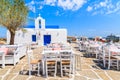 Tavern tables on a square with typical white Greek church in Naoussa port, Paros island, Cyclades, Greece Royalty Free Stock Photo